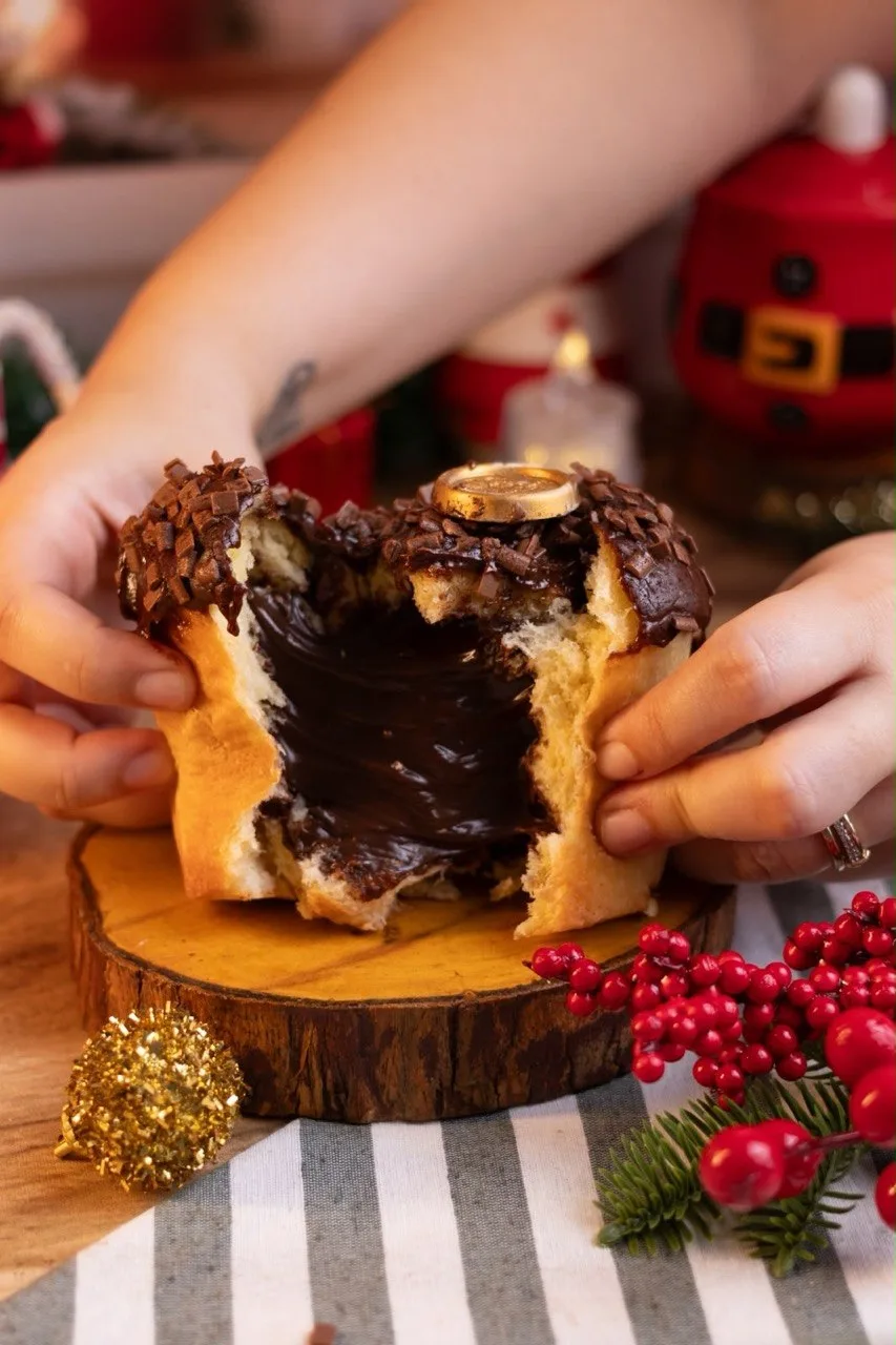 Mãos abrindo panetone recheado com creme de chocolate escorrendo